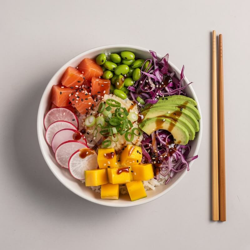 Colorful poke bowl with fresh tuna, avocado, edamame, and rice, top-down view.