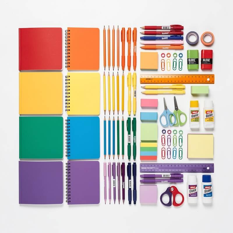 Back-to-school flat lay with notebooks, pencils, and supplies on a clean white surface.