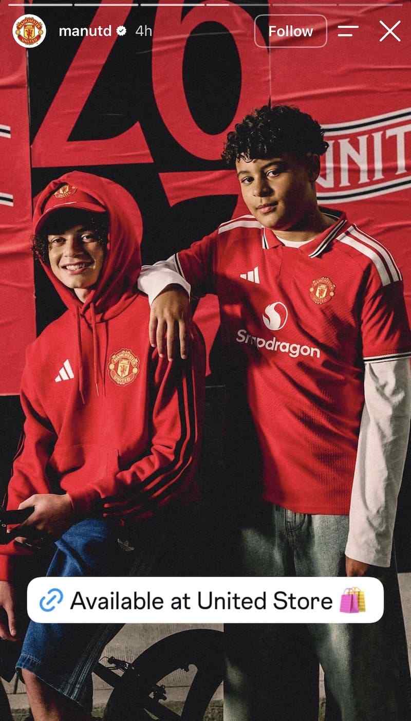 Two young fans in red ManUtd kit against large club banner, Available at United Store link sticker.