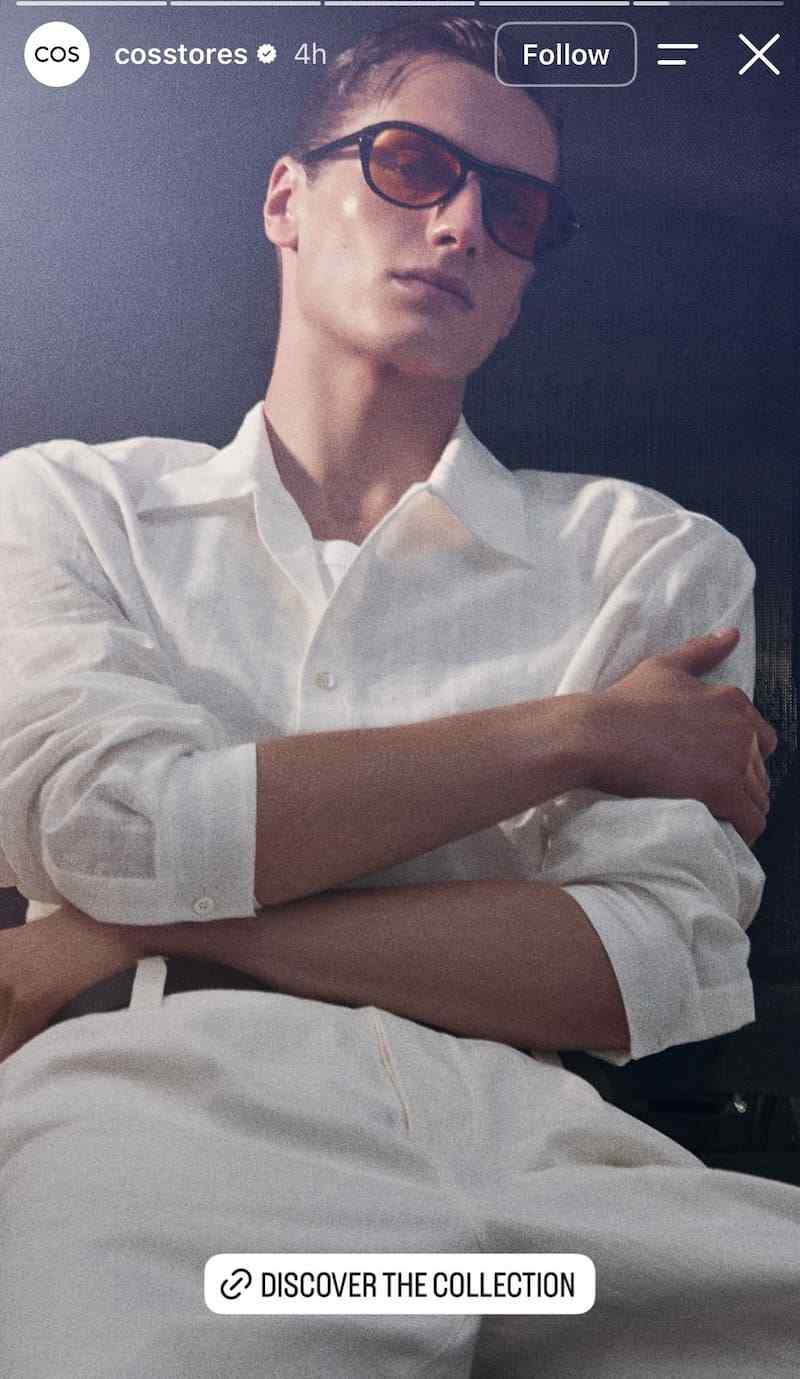 Model in white linen shirt and amber sunglasses against dark moody background, DISCOVER THE COLLECTION link sticker.
